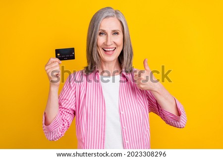 Photo of aged woman happy positive smile show thumb-up like fine ad credit card isolated over yellow color background