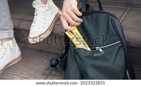 Close-up of a girl crouched on the steps for a light snack. She pulls a protein bar out of her women's backpack. Diet and monitor nutrition Royalty-Free Stock Photo #2023322831