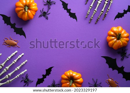 Halloween decorations on purple background. Happy Halloween concept. Flat lay pumpkins, bony hands, bats silhouettes, spiders.