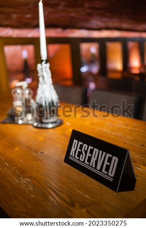A modern idea for a reserved table with the inscription Reservation of your place. Idea restaurants the inscription reserved on a wooden table in a cafe. Royalty-Free Stock Photo #2023350275