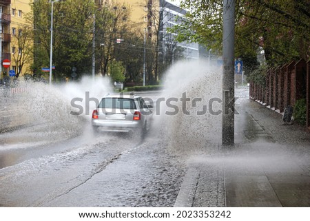 05.05.2021 wroclaw, poland, During a downpour, the car falls into a pool of water on the road, causing a splash. Royalty-Free Stock Photo #2023353242