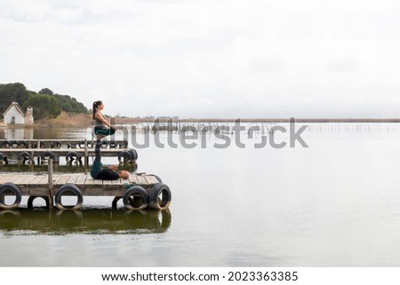 Couple practicing acroyoga in nature, a lake and a wooden dock. Horizontal picture