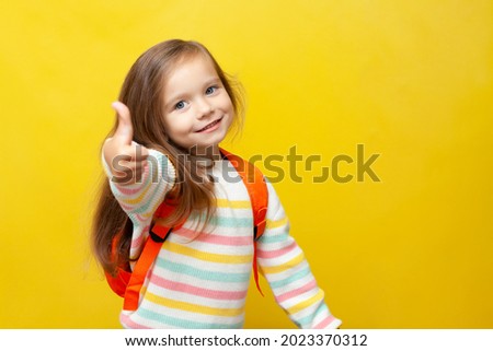 Portrait of a cute cheerfully laughing girl with a backpack. Back to school. Emotions. Joy. Yellow background, space for text. High quality photo