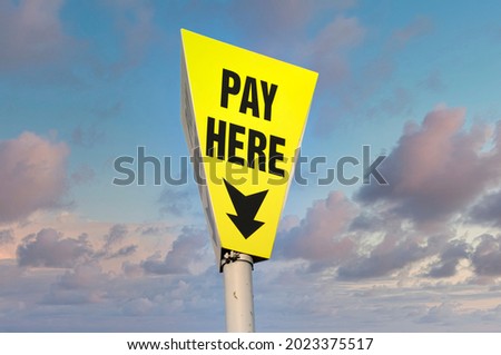 Pay here yellow sign with arrow against sky