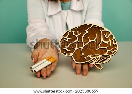 Wooden model of brain and cigarette in the hands of a nurse. Smoking addiction