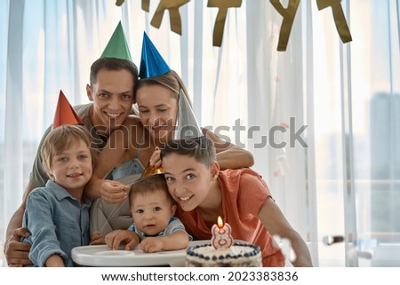 Happy young family with friends celebrates birthday of a child of 8 months. The first year of life. Home party.
