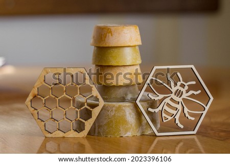 Natural bee wax in different shades of orange, around shape, placed on table for product photography for sale. With it symbol of bee and honeycomb pattern presented for more interesting picture