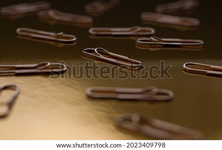 Gold paper clips on a gold background. School minimalism.