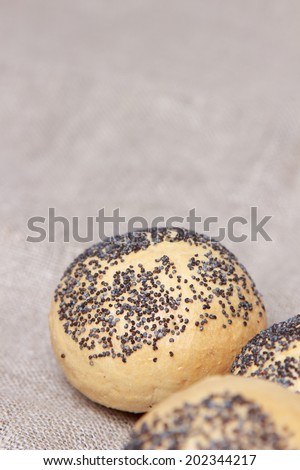 round buns with poppy seeds over canvas (linen or burlap) background