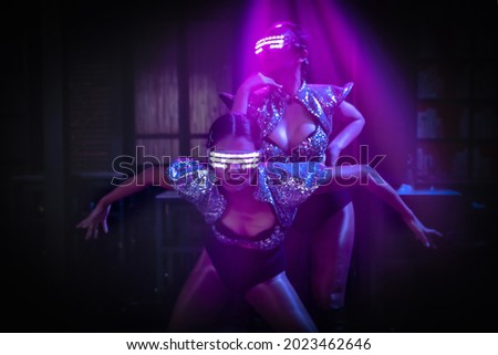 two dancers in modern costume showing techno dance performance in disco and nightclub with neon and spotlight with selective focused Royalty-Free Stock Photo #2023462646
