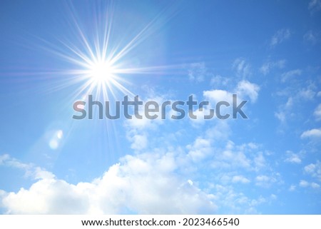 Blue sky with white fluffy clouds and sun reflection. Sunny background. Sun appear directly above Thailand. The afternoon summer sun shines on a beautiful sky with clouds. Hot weather, summer season. Royalty-Free Stock Photo #2023466540
