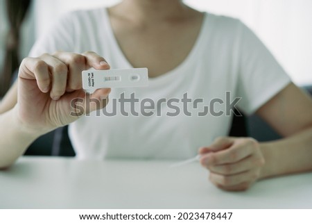 Asian young woman with face mask using SARS 2019-nCoV COVID-19 coronavirus antigen rapid test kit - ag test kit at home. Positive result of COVID-19 antigen rapid test. Royalty-Free Stock Photo #2023478447