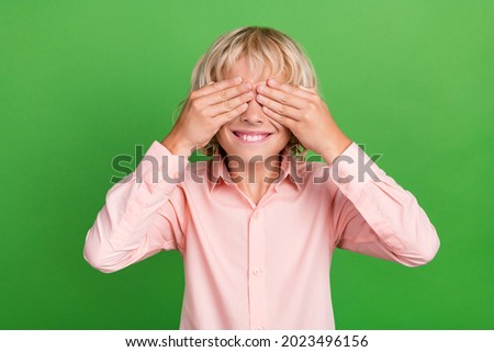 Photo of young cheerful positive cheerful boy hold hands cover face eyes isolated on green color background