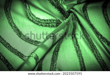 fabric is transparent emerald green with brightly innate stripes, the material allowing the light to pass through it so that the objects behind are clearly visible.