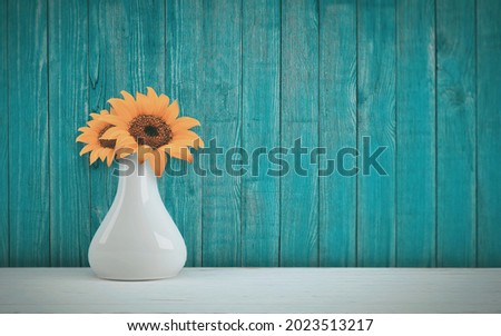 Sunflowers inside white pot in blue wooden background looks outstanding 