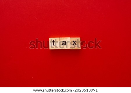word TAX made of wooden letters on red background with copy space
