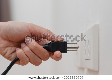 Men's hands are Plug in power outlet adapter cord charger of laptop computer On wooden floor With sun Warm light Royalty-Free Stock Photo #2023530707
