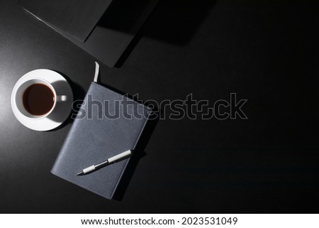 top view of office workspace Black table with notebook, keyboard, notepad, pen and a cup of coffee with copy space, simulated flat.