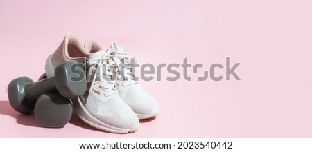 Female sneakers and dumbbells on large background  for banner. Essential equipment for sport workout