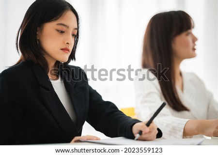 Asian business hold a small meeting inside the office or conference room. Brainstorm to exchange ideas. There are stock boards Laptops and tablets are communication tools. Unity teamwork concept.