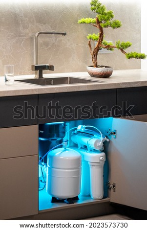 House water filtration system. Osmosis deionization system. Installation of water purification filters under kitchen sink Royalty-Free Stock Photo #2023573730