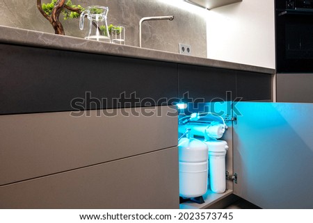 House water filtration system. Osmosis deionization system. Installation of water purification filters under kitchen sink Royalty-Free Stock Photo #2023573745