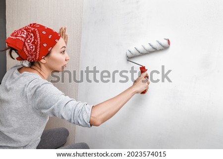 Applying primer and glue with a wide roller on the plastered surface of the wall for wallpapering Royalty-Free Stock Photo #2023574015