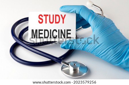Card with text STUDY MEDICINE supplies, pills and stethoscope. Medical