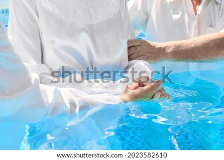 Two pastors baptize a women in the name of Christ Royalty-Free Stock Photo #2023582610