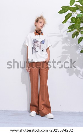 Fashion full body model Posed on with a shadow green leaves
background in fashion clothes on studio
