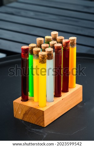 multi-colored test tubes with different chemicals are placed in a special rack on the table. red, yellow and blue multicolored test tubes close-up