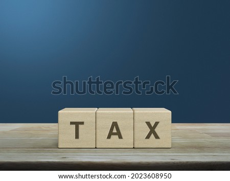 TAX letter on block cubes on wooden table over light blue gradient background, Business and finance concept