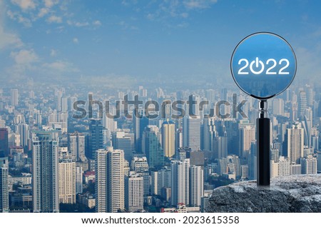 2022 start up flat icon with magnifying glass on rock mountain over modern city tower, office building and skyscraper, Business happy new year 2022 cover concept