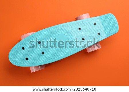 Turquoise skateboard on orange background, top view