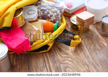 Schoolbag with different products on table. Concept of Backpack Food Program Royalty-Free Stock Photo #2023648946