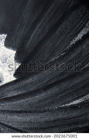 Black background sprinkled with flour, smeared flour, table for cooking, rolling dough. Blank space for menu text, recipe, ingredients, Or Christmas background with snow on a dark background 