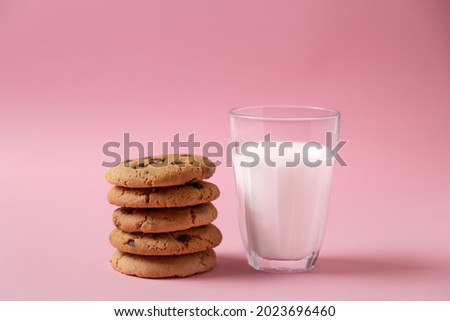 chocolate chip cookies and glass of milk in pink background
