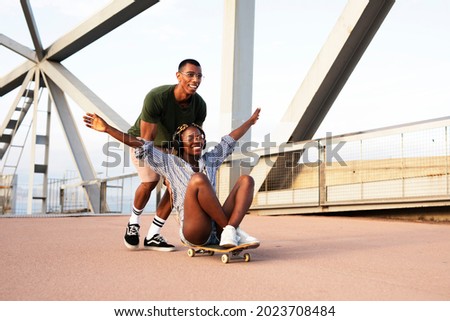 Beautiful couple having fun outdoors. Portrait of an excited young couple with skateboard. Royalty-Free Stock Photo #2023708484