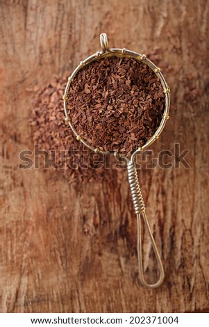 hot chocolate flakes with chilli flavor in old rustic style silver sieve, shallow dof