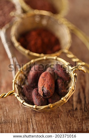 cocoa beans in old rustic style silver sieves on old wooden background