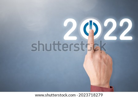 Finger pressing blue start 2022 button on virtual interface on gray background with copy space for text. Concept of new year. Businessman pressing 2022 start up business. Beginning of New Year 2022 Royalty-Free Stock Photo #2023718279