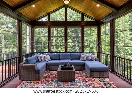 New modern screened porch with patio furniture, summertime woods in the background. Royalty-Free Stock Photo #2023719596