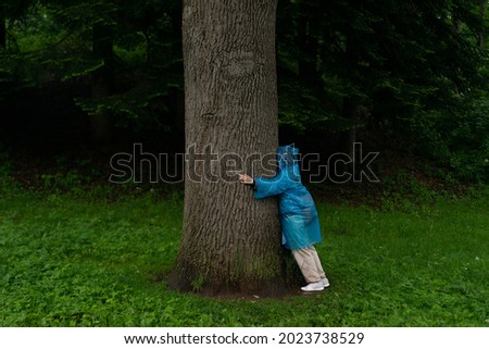 Young woman leaning to tree trunk in summer forest.