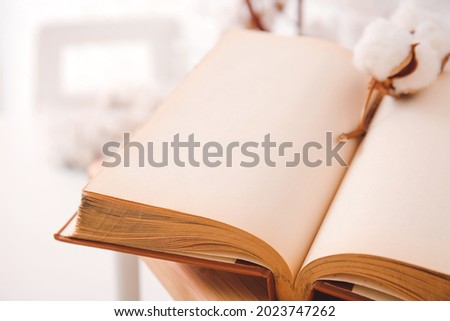 Open old book and cotton flower, closeup