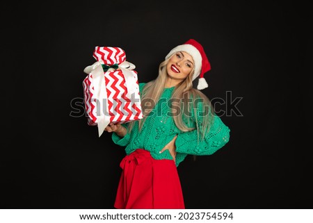 Close-up portrait of beautiful woman in santa hat with toothy happy face, black background, copy space, studio shot, weared in green red color