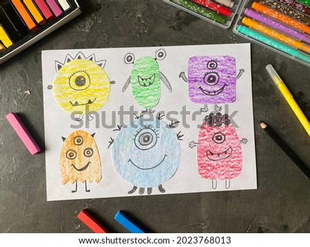 Funny monsters drawn on paper, pencils and markers on the table. Kids DIY