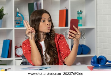 funny teen girl making video on selfie using mobile phone showing peace gesture, blogging