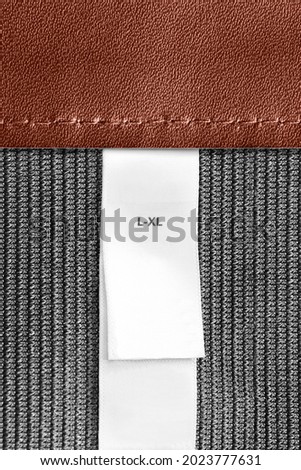 Size L-XL clothing label on leather and textile background