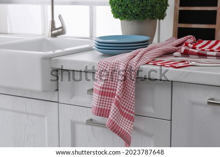 Different towels and stack of plates near sink on kitchen counter Royalty-Free Stock Photo #2023787648