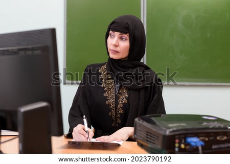 Muslim girl teacher working with school documents.